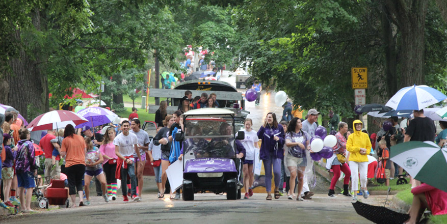 Paraders walk down a tree-lined street.