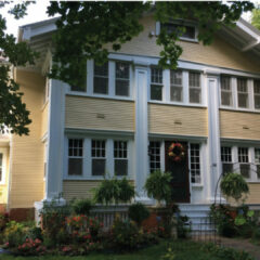 photo of a historic two arts and crafts style story home painted a cheerful yellow with white trim