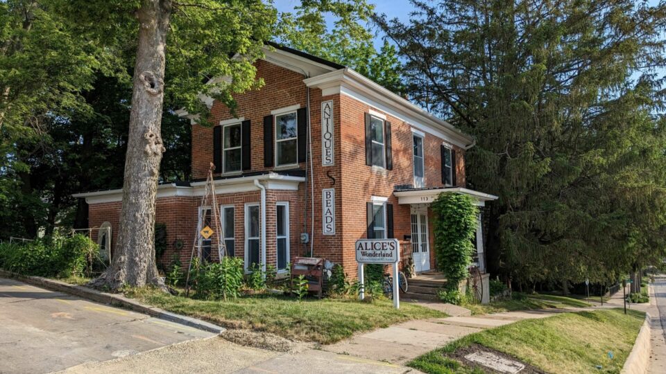 2 story brick home with a brick addition on the back in a wooded and rustic landscaped yard