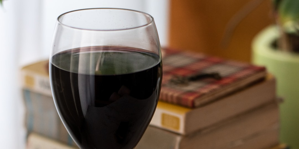 Glass of red wine by stack of books