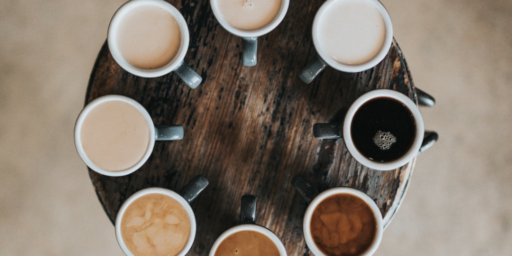 Looking down at a circle of a variety of types of cups of coffee