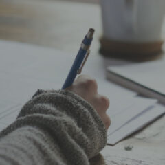 Close up view of handwriting on papers with a book and notebook nearby