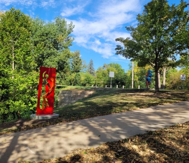 colorful large (6' plus) metal artwork sculptures installed along an outdoor walking path